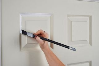 A smaller Harris paint brush being used for detailing work on an internal door