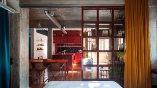 studio apartment with room divider shelves, red kitchen, mustard yellow curtain