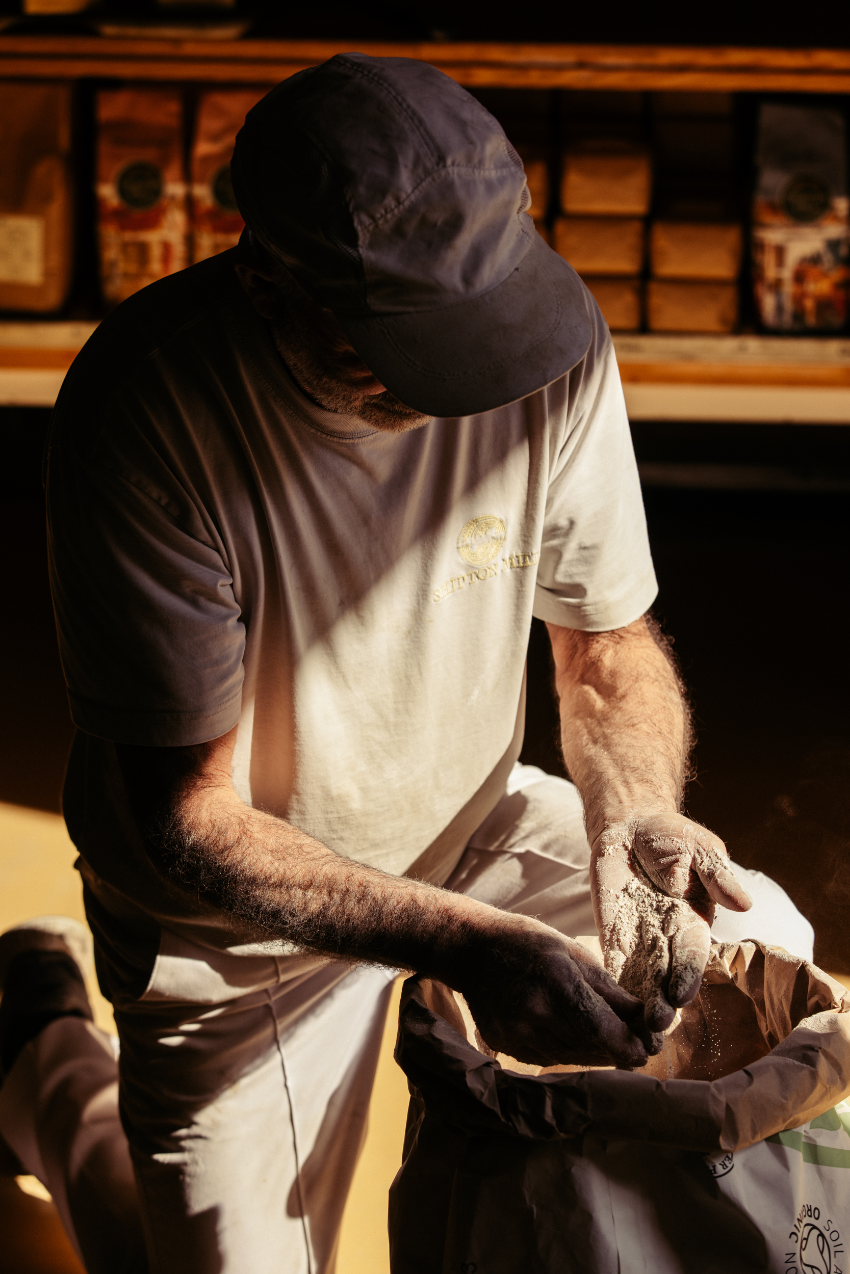 Miller on a bent knee checking the quality of a sack of flour