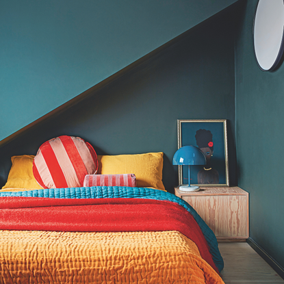 teal drench bedroom with brigt red and orange bedding