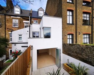 Two storey rear extension finished in white render on terraced house with open bifold door