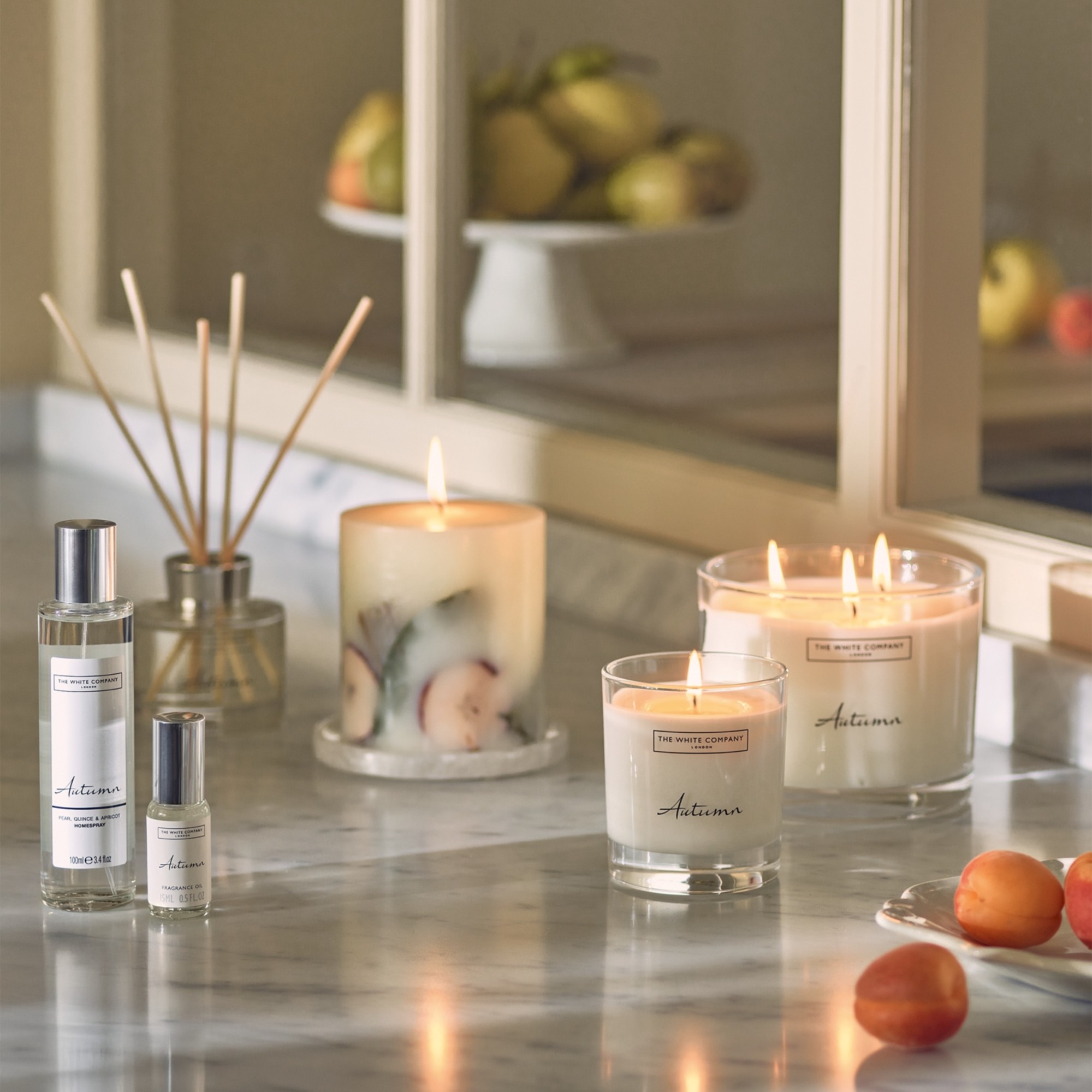 The White Company Autumn home fragrance range on a kitchen worktop with some appricots