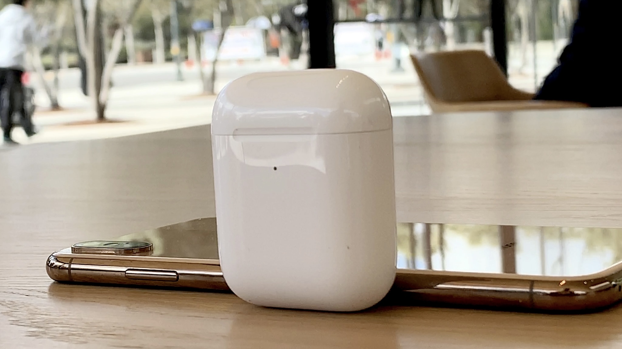 AirPods 2 Wireless Charging Case standing on table with gold iPhone XS behind
