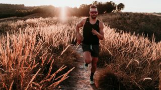 Man running through field wearing trail running sunglasses