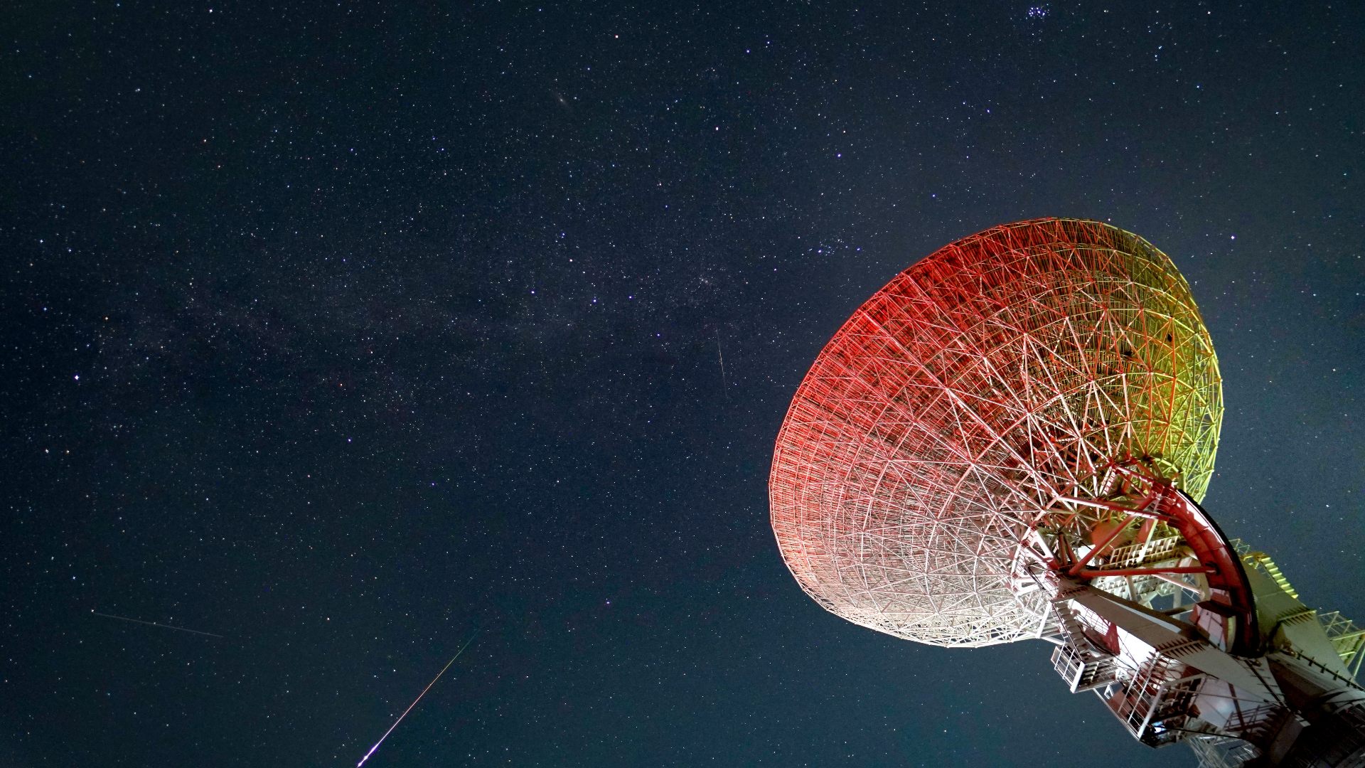 Parlak Prusya meteorları, görüntünün sağındaki büyük teleskop çanağıyla birlikte yıldızlı gökyüzünde ilerliyor.
