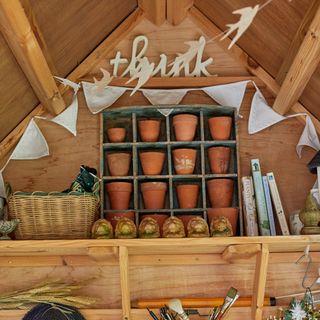 Interior of wooden shed with small terracotta pots and wooden shelf