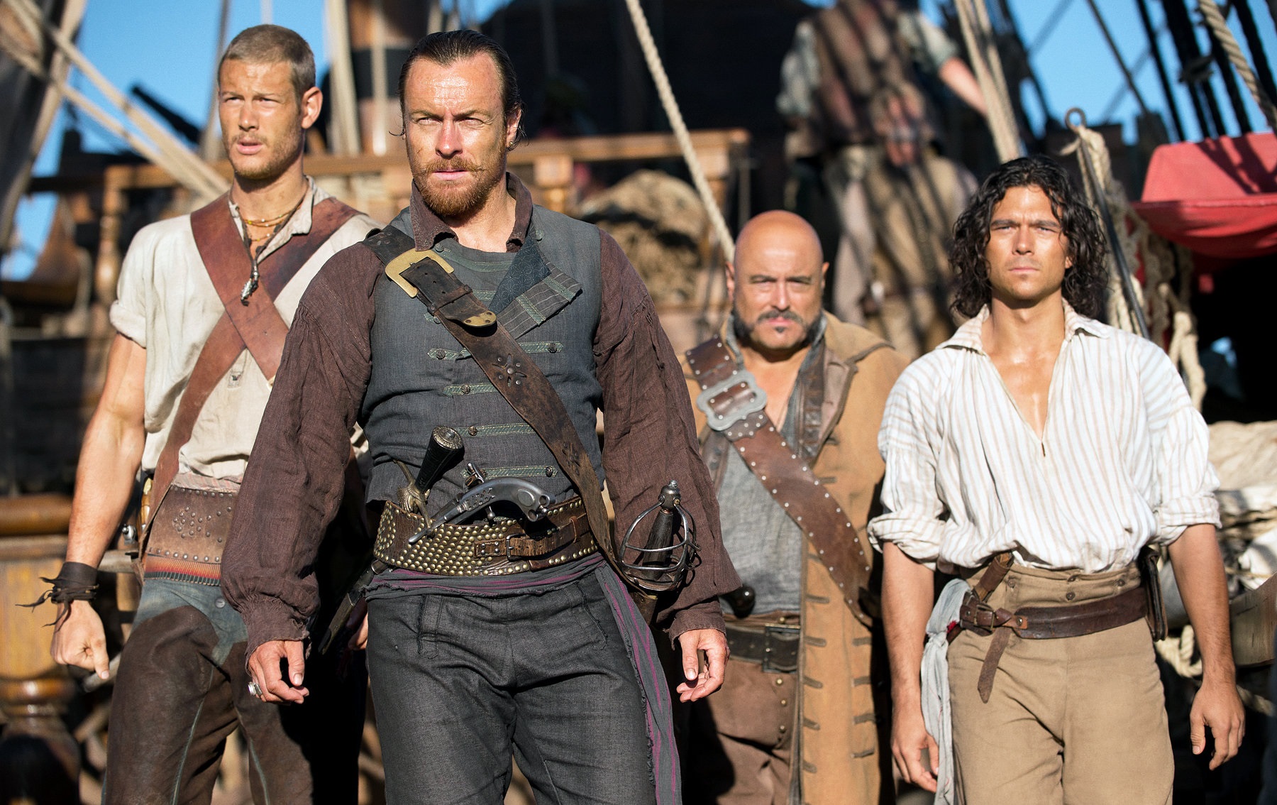 En del av besättningen i Black Sails står uppe på däck och kollar ut mot något.