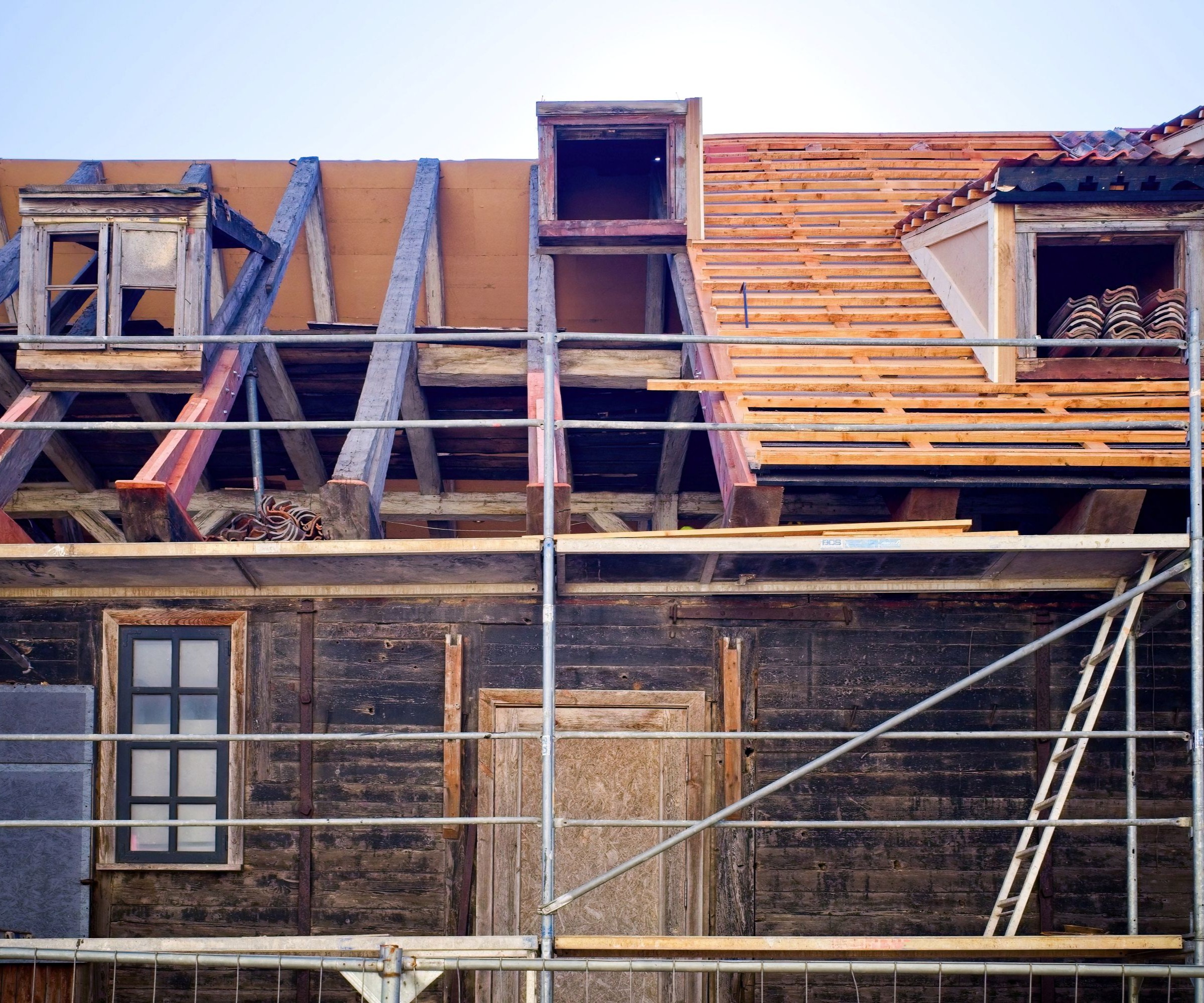 An old barn with scaffolding around it and the roof being repaired
