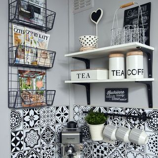 Black and white kitchen shelving with patterned tiles on wall