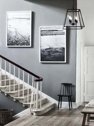 large Browning lantern pendant in a gray hallway by a staircase with wall art