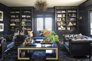 dark blue sitting room with book cases and black leather chairs