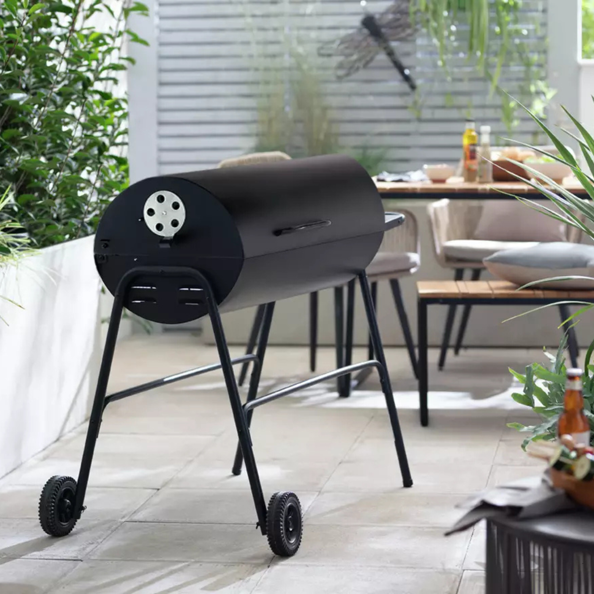 Argos Home Drum Charcoal BBQ With Cover &amp; Utensils in a modern courtyard garden.