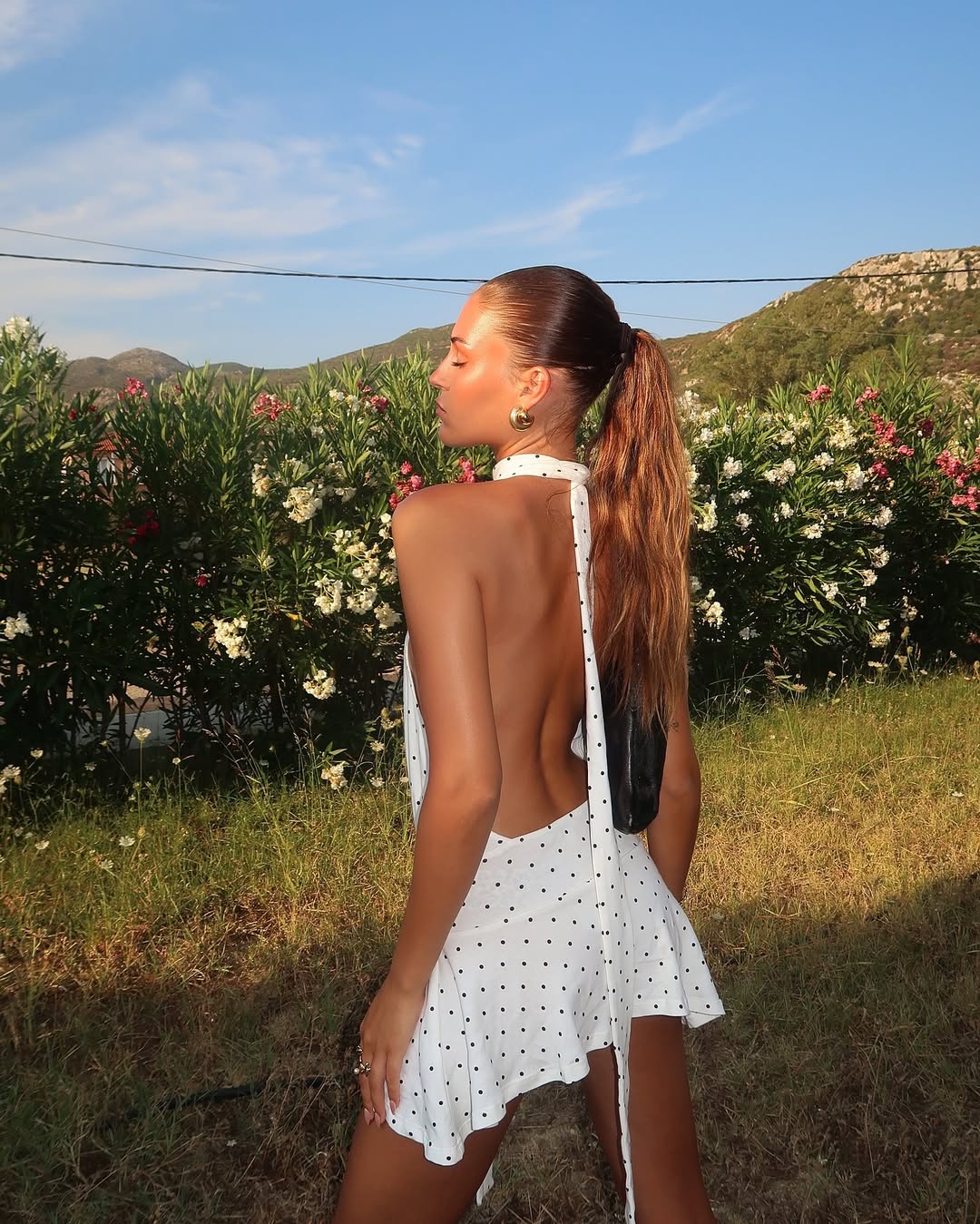 Influencer Tegan Barker in a backless halter neck white on black polka dot dress