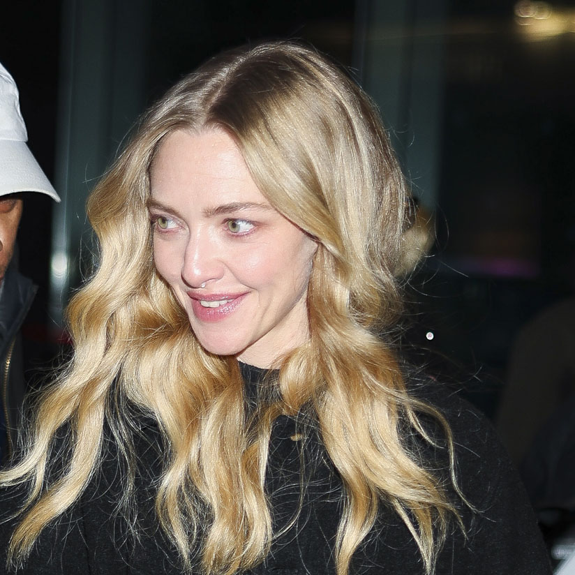 Amanda Seyfried wearing a black shacket, blue jeans, black boots, and a black woven bag