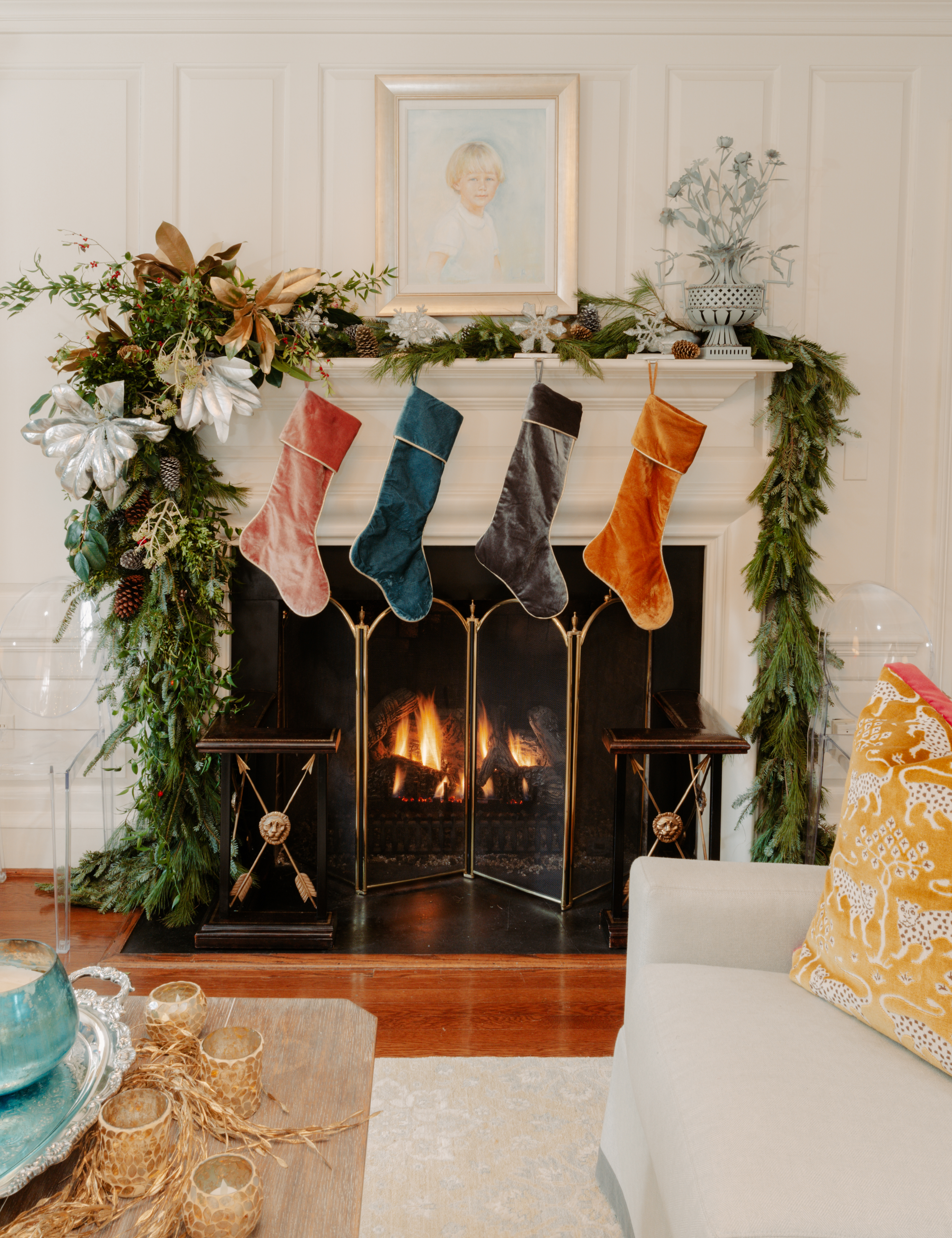 Cozy holiday living room featuring asymmetric garland and a row of five multicolored velvet stockings