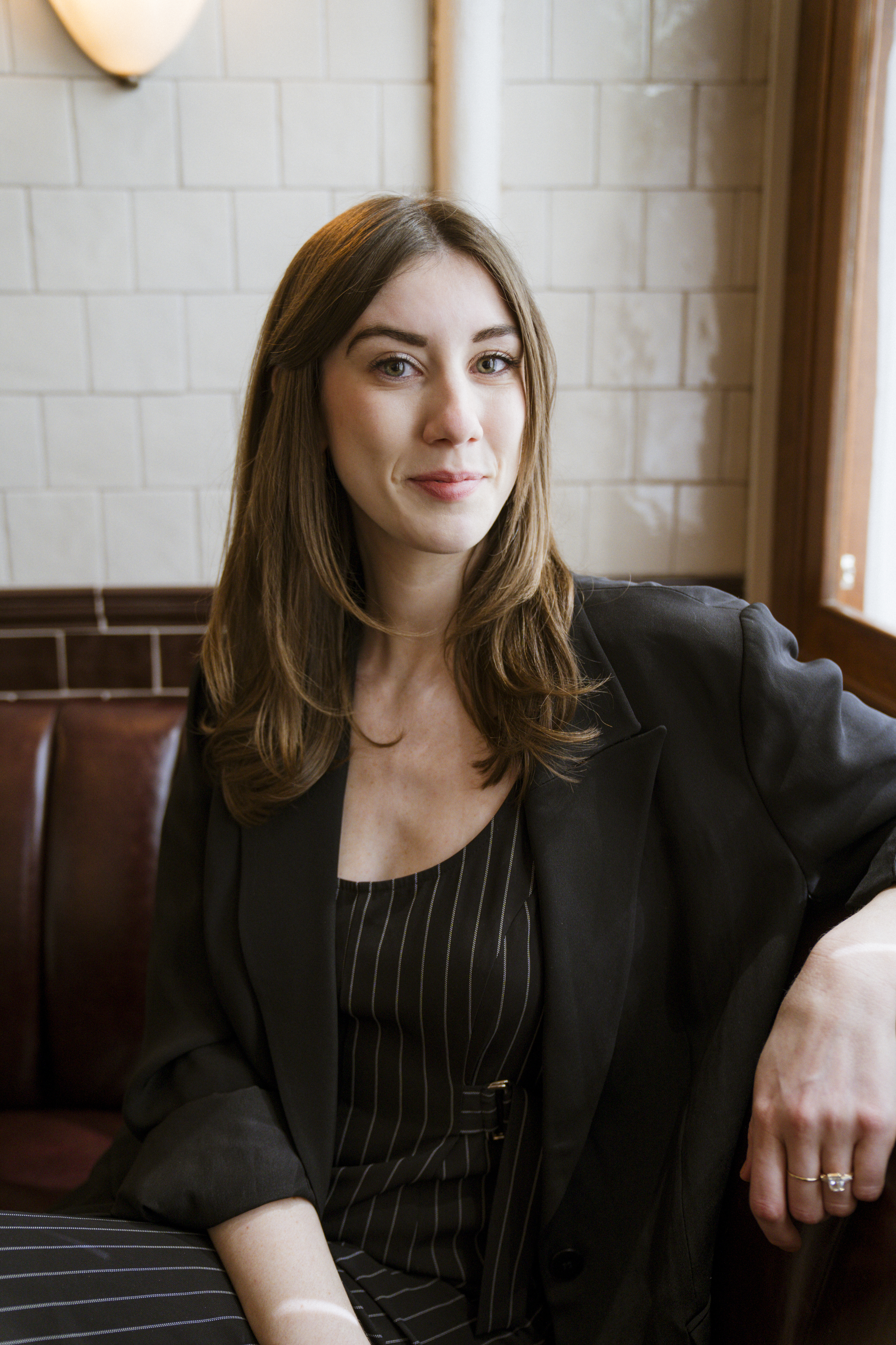 woman with long dark hair and pinstriped outfit