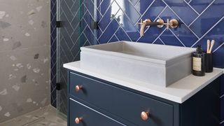 bathroom with blue herringbone tiles and navy blue sink vanity unit to show the bathroom trend for mixing blue colors