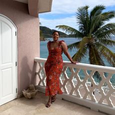 Woman wearing a red floral-print dress on a balcony