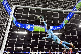 Real Madrid's Belgian goalkeeper #01 Thibaut Courtois lunges for the ball before Manchester City's Spanish midfielder #14 Nico Gonzalez (out of frame) scored their first goal during the UEFA Champions League knockout phase play-off football match between Real Madrid CF and Manchester City at the Santiago Bernabeu stadium in Madrid on February 19, 2025.