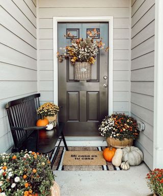 Front door with fall flowers and pumpkins