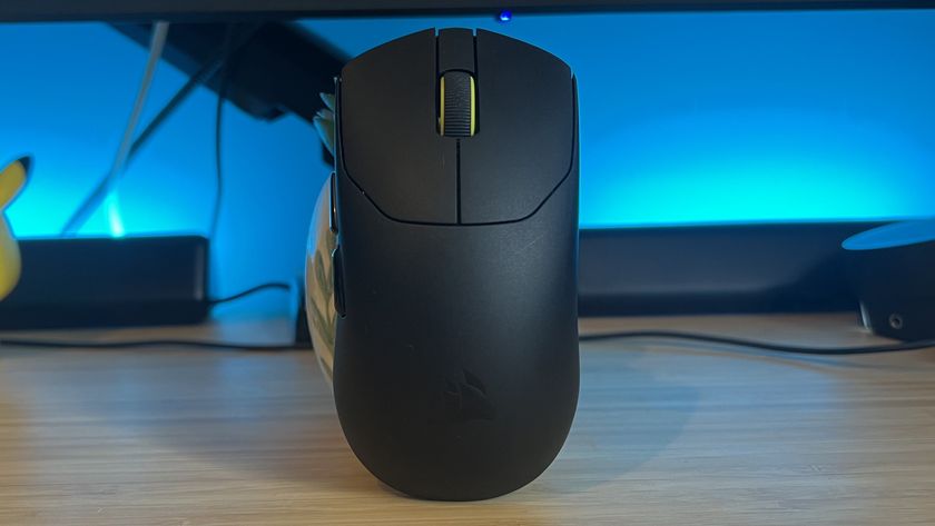 Corsair Sabre Pro V2 Ultralight gaming mouse on a wooden desk with blue backlighting