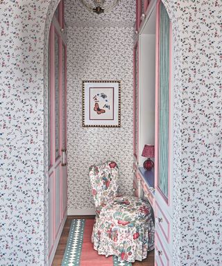 patterned wallpaper walk in dressing area with pink joinery and patterned chair