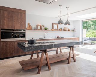 a modern dark wood kitchen with freestanding island with marble slab by Naked Kitchens