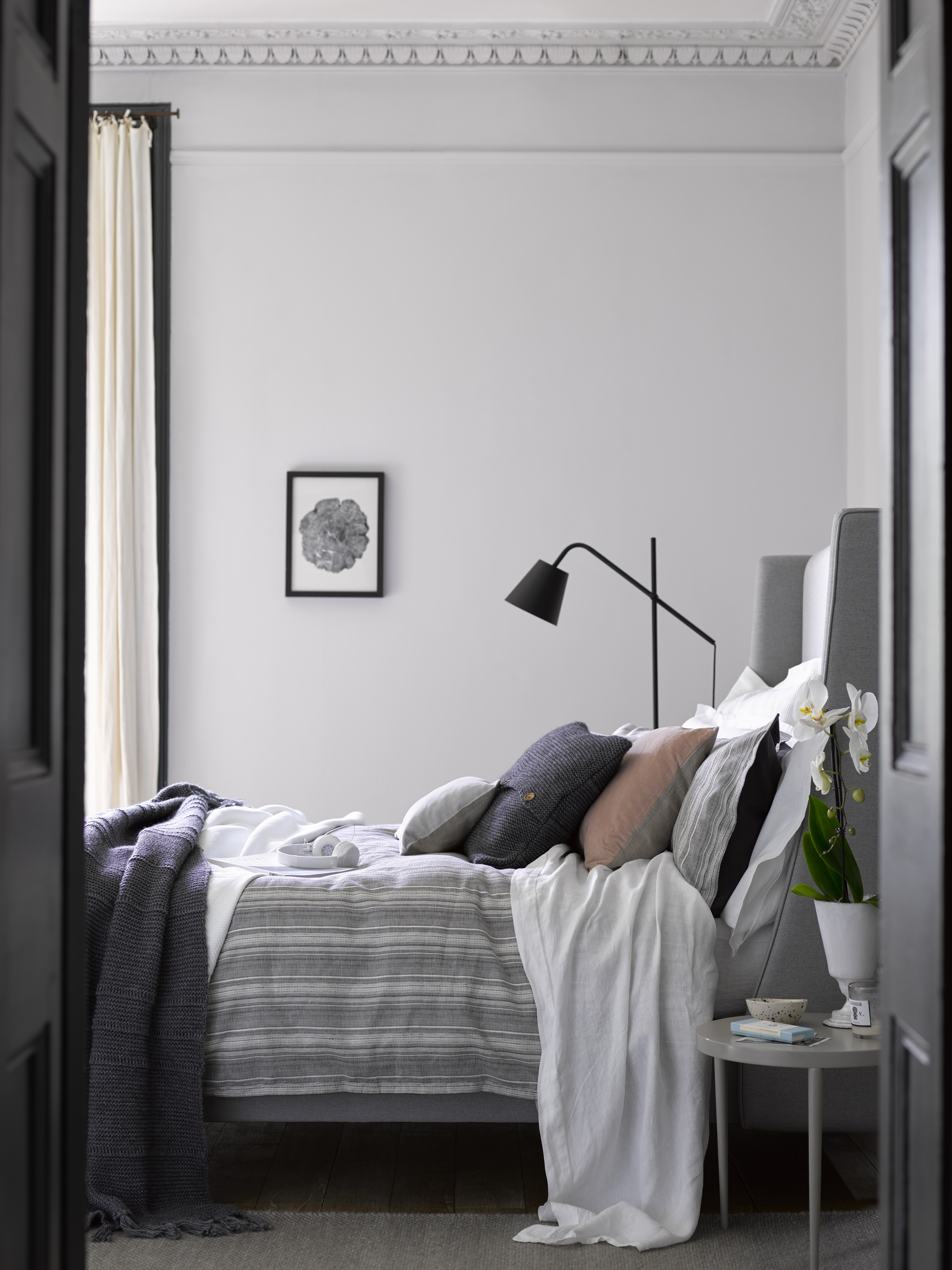 A muted gray bedroom scheme with white, blush and navy soft furnishings and black metal lighting illustrates how to choose the best bedroom colors.