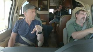 Mike Rowe talking with someone in a vehicle on Dirty Jobs