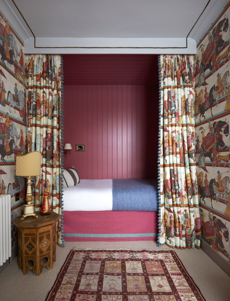 A bright pink bedroom nook surrounded by statement wallpaper and matching curtains