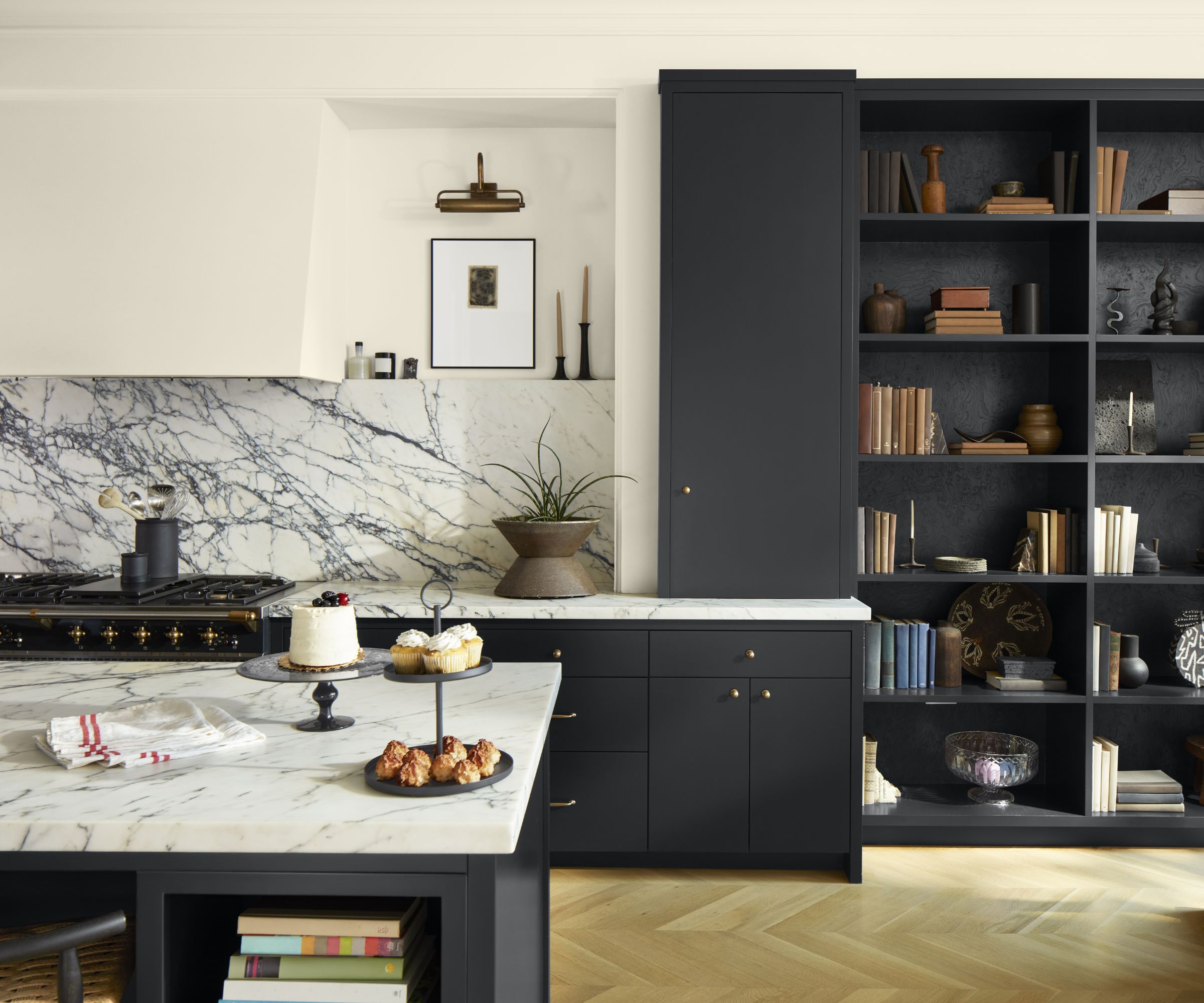 A kitchen with black cabinets, white walls, and a marble countertop and backsplash