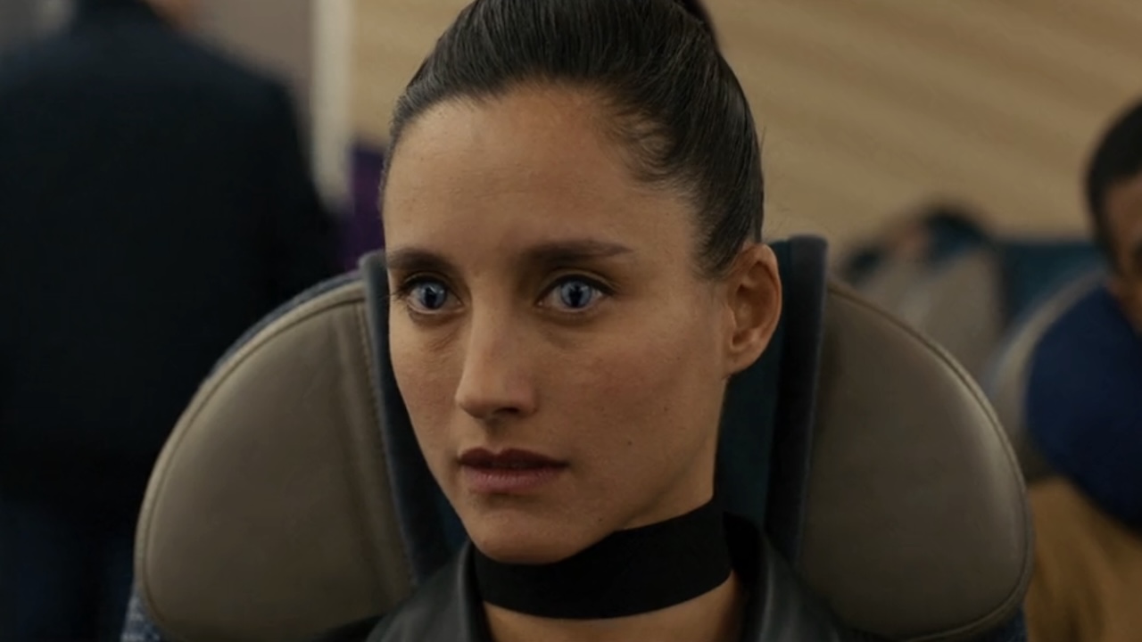 「ファイト・オア・フライト」の飛行機の座席に座る、奇妙な目をした女性暗殺者