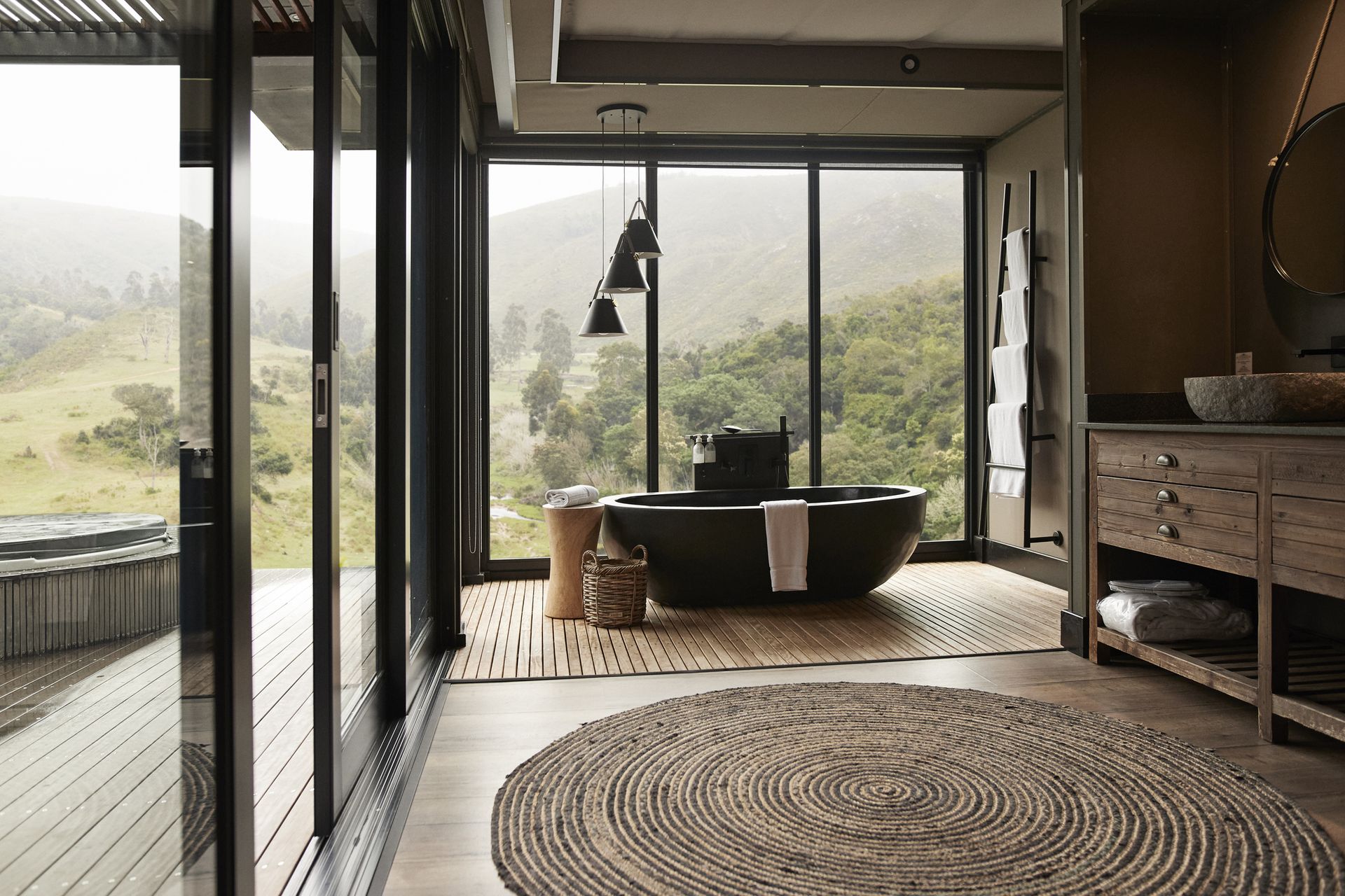 Pendant light hanging over bathtub in a bathroom with a large window.