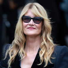 Laura Dern wears dark sunglasses and black trousers at an event. 