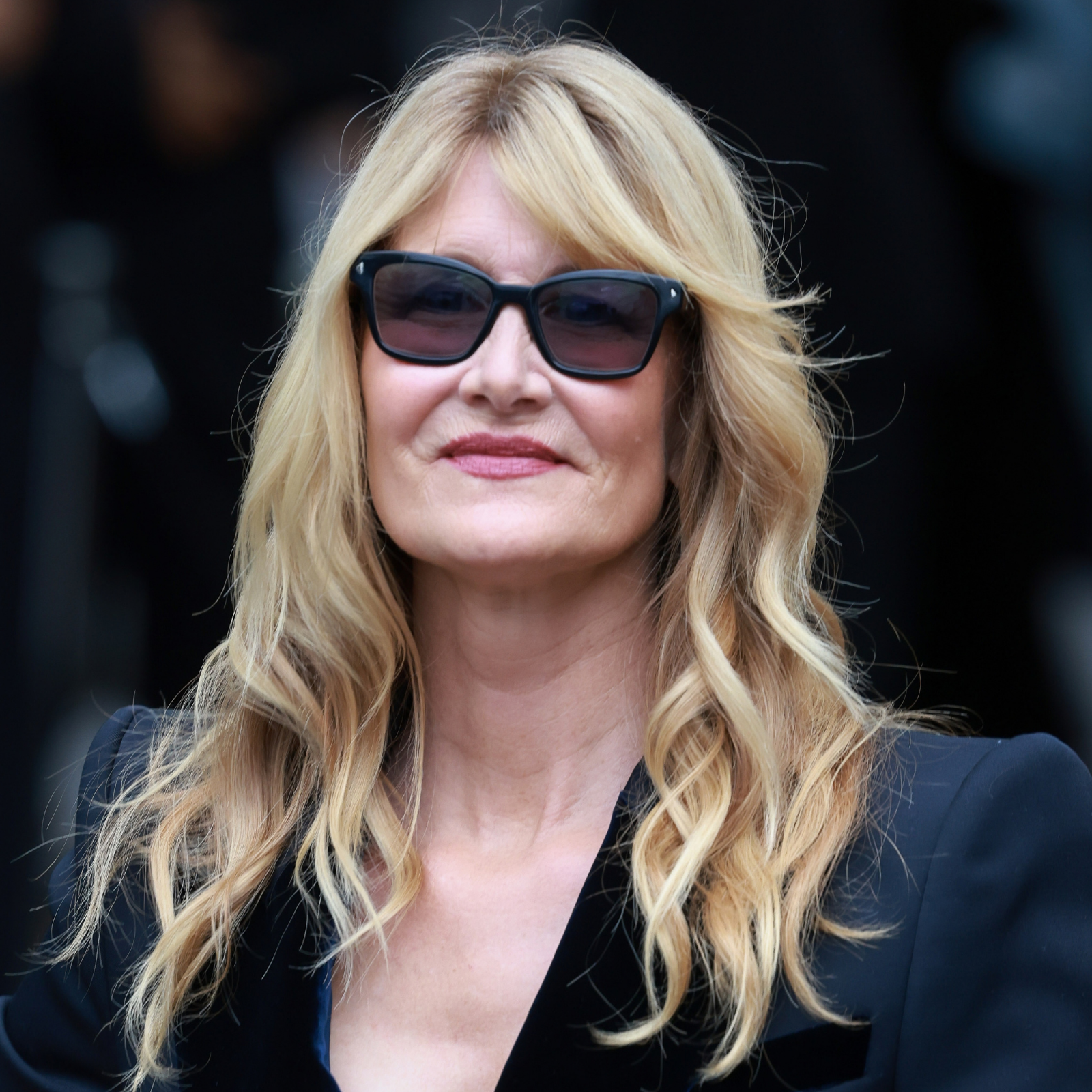 Laura Dern wears dark sunglasses and black trousers at an event.