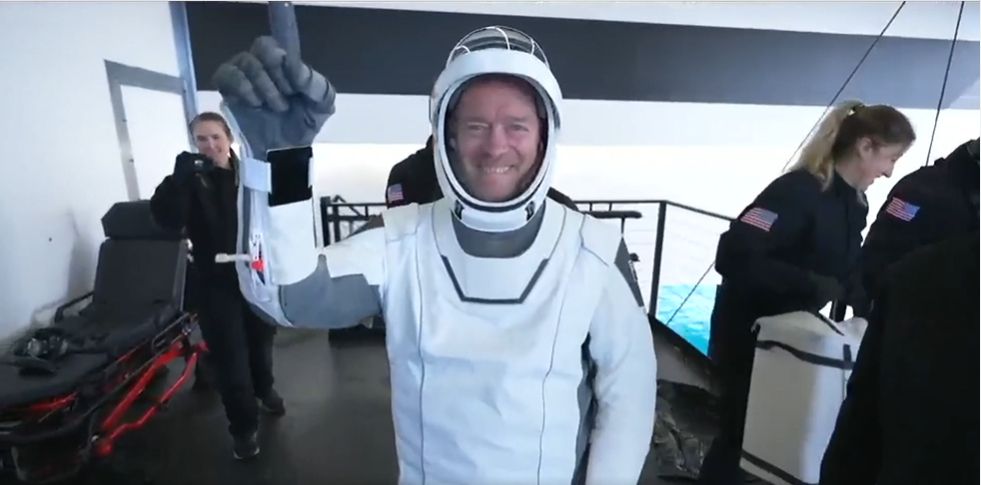 astronauts hold wave aboard a spaceship