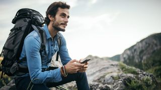 男子在徒步旅行时使用手机上的导航应用程序