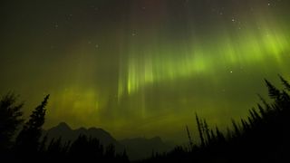 The Northern Lights appear in the sky through a layer of smoke caused by multiple wildfires in the early hours of September 4, 2022 in Banff National Park, Alberta, Canada. 