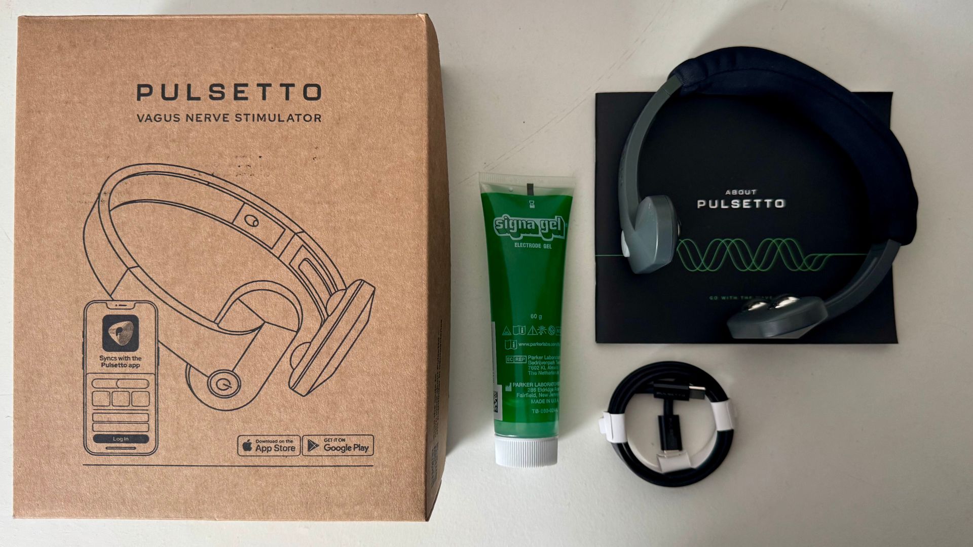 The Pulsetto neckband with green tube of electrode gel, a charger and box