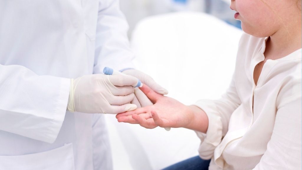 young girl receiving a finger prick test at the doctor&#039;s office