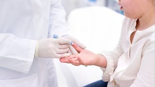 young girl receiving a finger prick test at the doctor's office