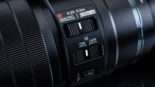 Studio image of the OM System 90mm macro lens close up of controls on lens barrel