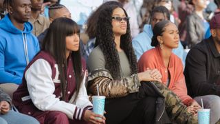 Geffri Maya as Simone Hicks, Rhoyle Ivy King as Nathaniel Hardin and Netta Walker as Keisha McCalla watching a game in All American: Homecoming season 3