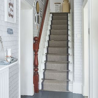 staircase with carpet and white brick wall
