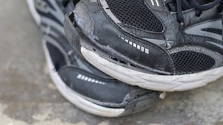 Pair of worn running shoes with sole separating from upper
