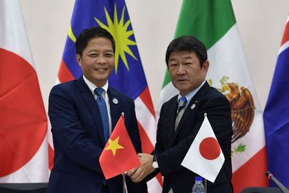 Vietnam's Trade Minister Tran Tuan Anh (L) shakes hands with Japan's Economic Revitalization Minister Toshimitsu Motegi (R) at the end of a Trans Pacific Partnership (TPP) press conference