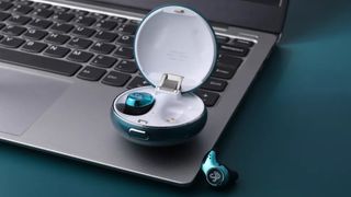 Earbuds and open charging case sitting on an open laptop