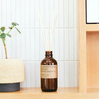 P.F. Candle Co. Teakwood & Tobacco Reed Diffuser on side by plant