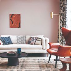 A pink-painted living room with wall art and patterned curtains