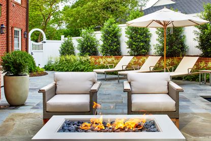 a firepit with chairs around in a modern backyard